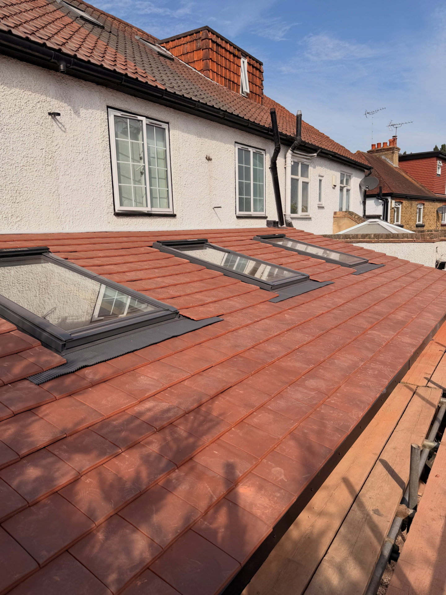 Three roof windows fitted into a newly tiled rear roof slope on a rendered home
