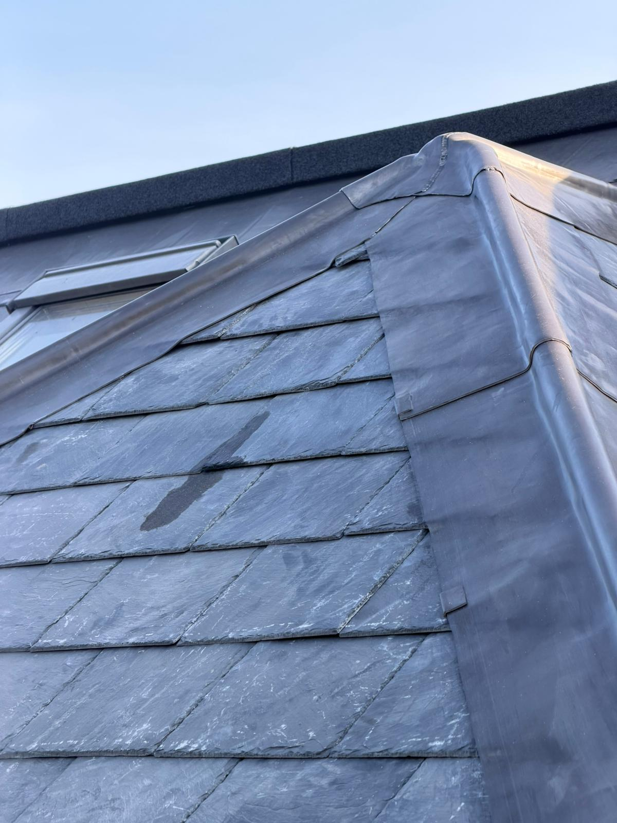 Well-maintained natural slate roof with clean lead flashing and hip detail