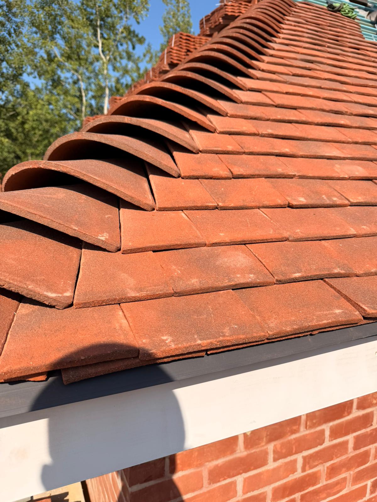 Half-round ridge tiles bedded over flat clay roof tiles