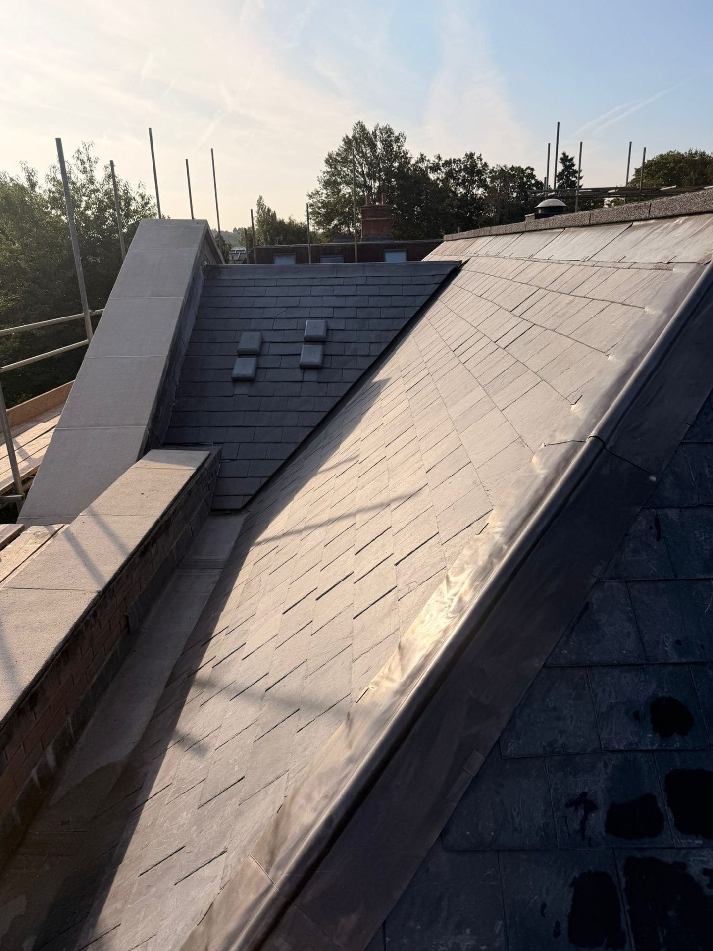 Lead valley and lead-covered roof section dressed between slate roof slopes