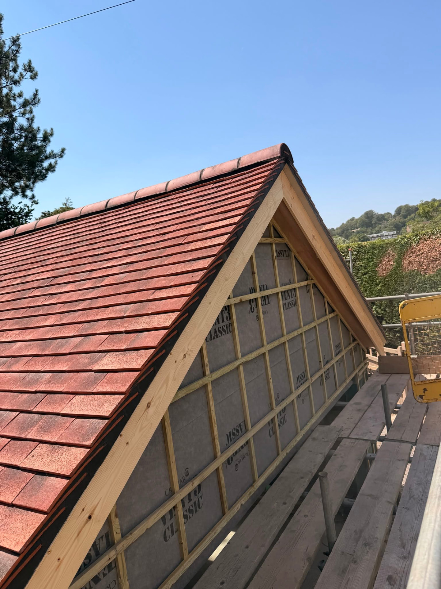 Finished clay tiled pitched roof and gable end against a blue sky